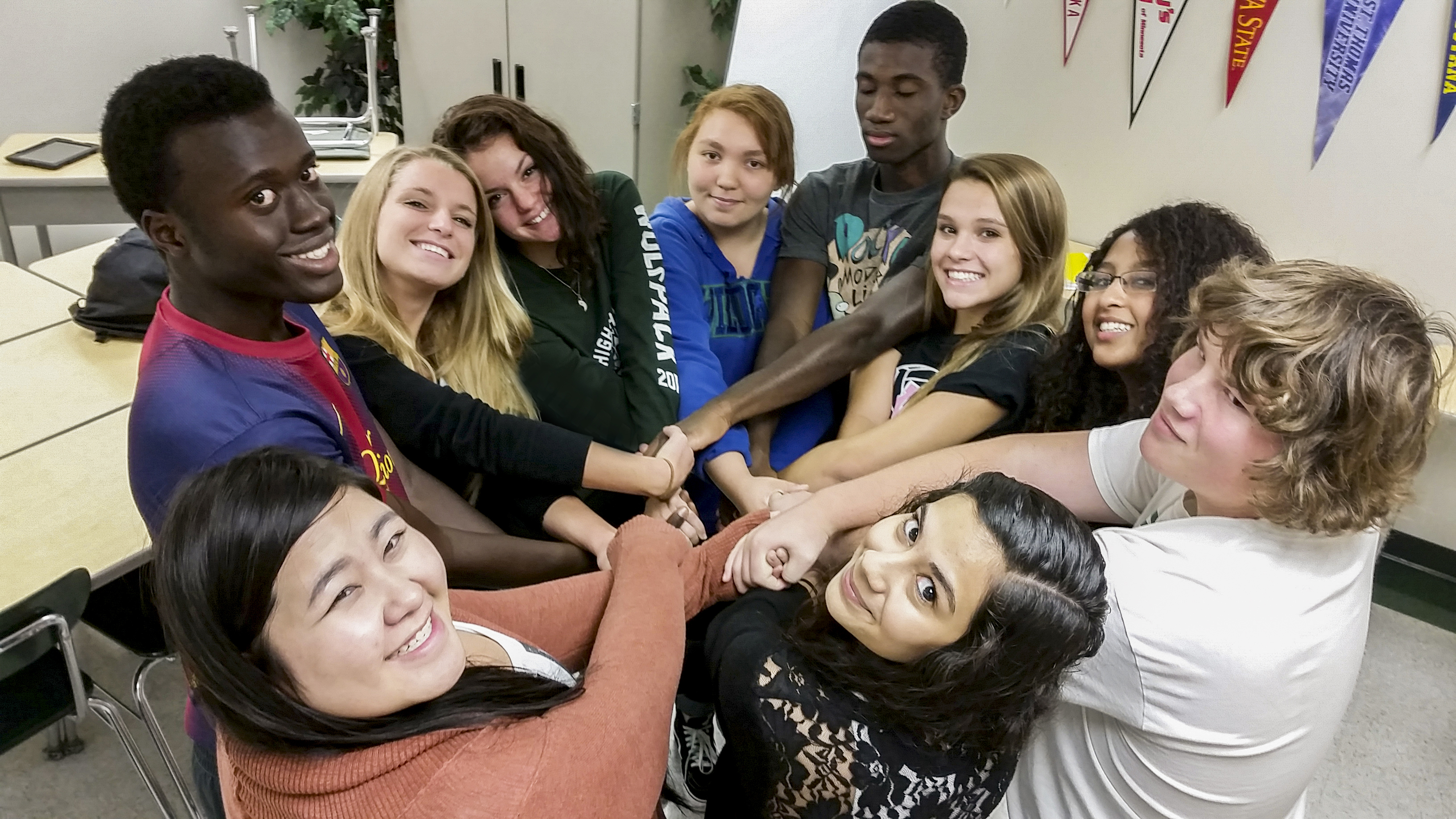 A group of AVID students holding hands in a human knot.