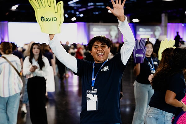 AVID student from the Summer Institute celebrates with both arms up.